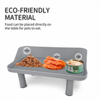 Gray feeder tray holding kibble, orange treats, and a green cat food can beneath ECO-FRIENDLY MATERIAL text