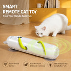 White cat watching smart remote cat toy with green feather tails on a wood floor